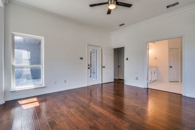 Unfurnished bedroom with crown molding, hardwood / wood-style floors, baseboards, ensuite bath, and a ceiling fan | Image 14