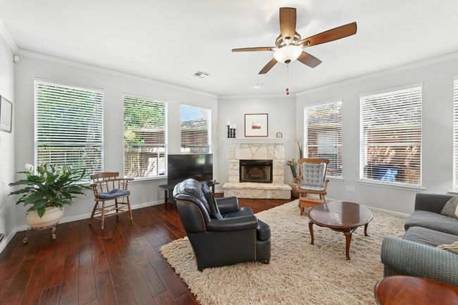 Living room with plenty of natural light, ornamental molding, hardwood / wood-style floors, a fireplace, and a ceiling fan | Image 4
