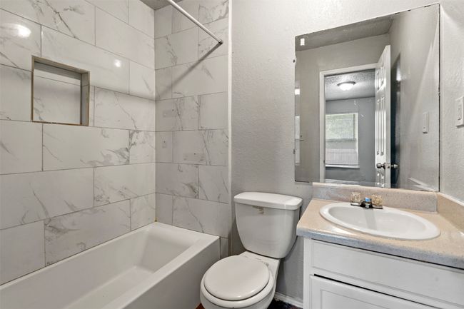 Full bathroom featuring vanity, toilet, a textured wall, and shower / tub combination | Image 25