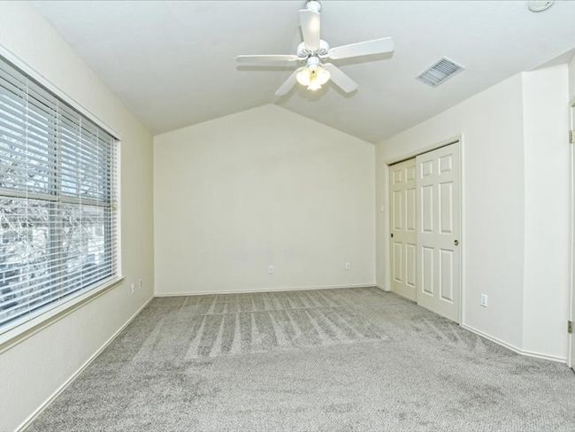 Unfurnished bedroom featuring vaulted ceiling, carpet flooring, baseboards, ceiling fan, and visible vents | Image 12