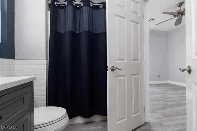 Full bathroom featuring vanity, curtained shower, ceiling fan, toilet, and visible vents | Image 19