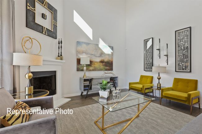 Living room featuring a fireplace with raised hearth, a high ceiling, wood finished floors, a skylight, and baseboards | Image 7