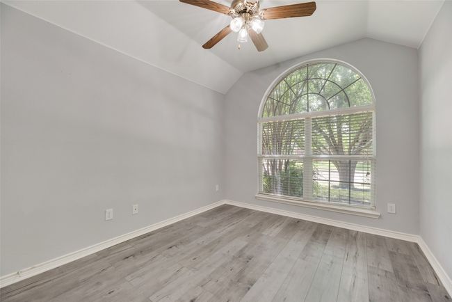 Empty room featuring healthy amount of natural light, vaulted ceiling, ceiling fan, wood finished floors, and baseboards | Image 12