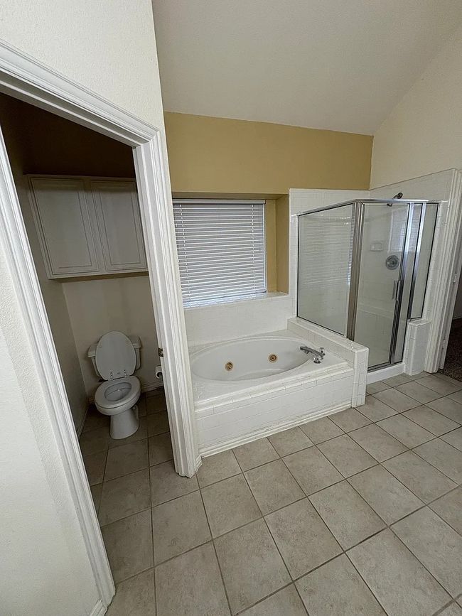 Full bath with a whirlpool tub, tile patterned flooring, a stall shower, and vaulted ceiling | Image 15