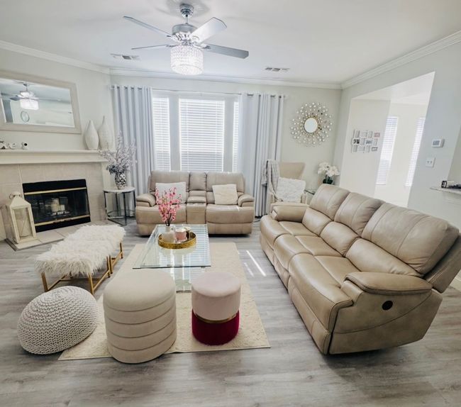 Living area with a ceiling fan, crown molding, wood finished floors, and a tiled fireplace | Image 12