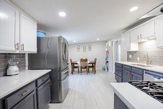 Kitchen with light countertops, a sink, white cabinetry, and dishwashing machine | Image 13
