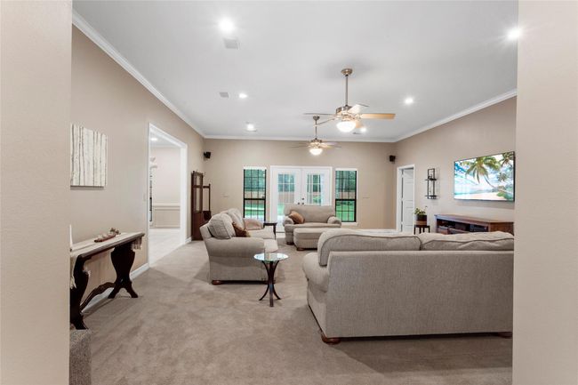 Large Family room with fresh neutral paint, recessed lighting, double ceiling fans and french doors open up to back patio. | Image 9