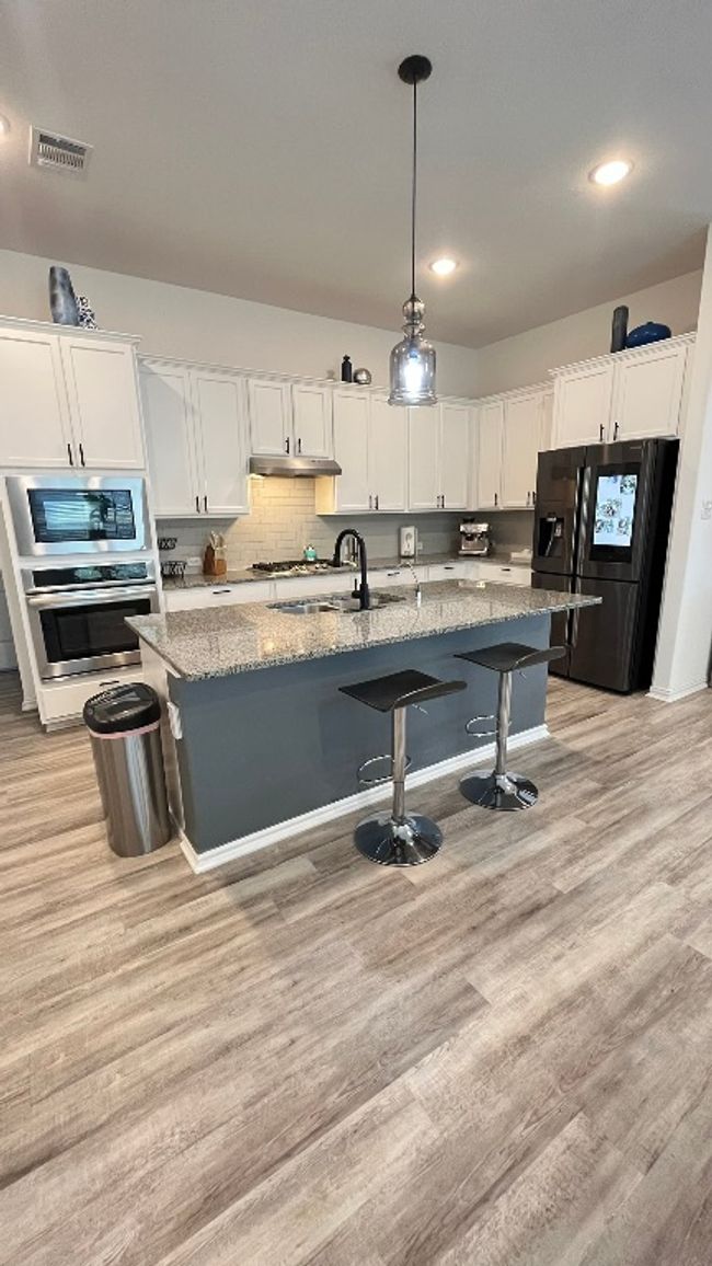 Kitchen featuring stainless steel appliances, under cabinet range hood, a sink, white cabinets, and recessed lighting | Image 8