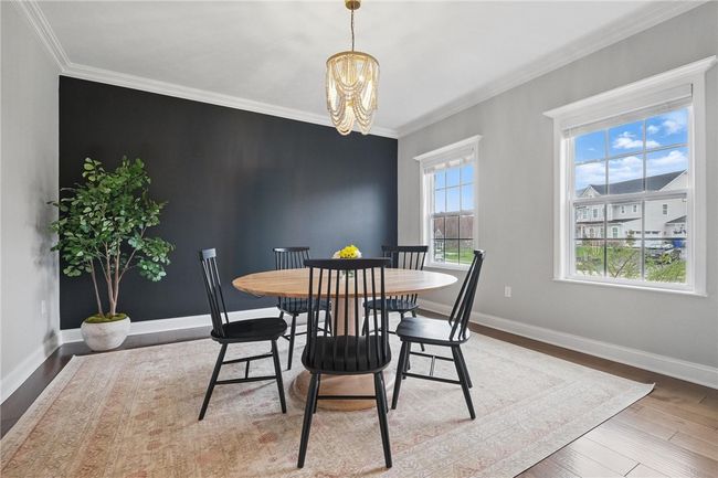Located just behind the French doors in the entryway, this versatile room features rich hardwood floors, crown molding, beautiful chandelier, large windows with abundant natural light, and a striking accent wall that adds modern elegance to the space. | Image 6