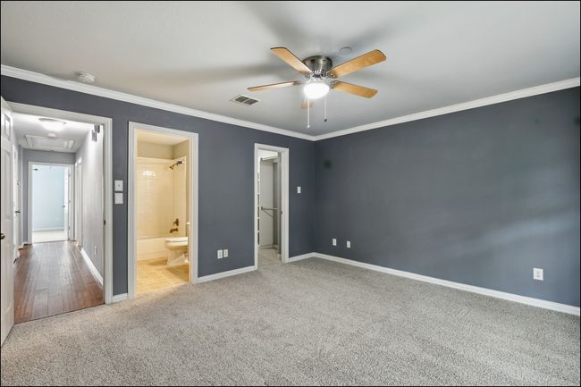 Unfurnished bedroom with crown molding, visible vents, baseboards, attic access, and carpet flooring | Image 17