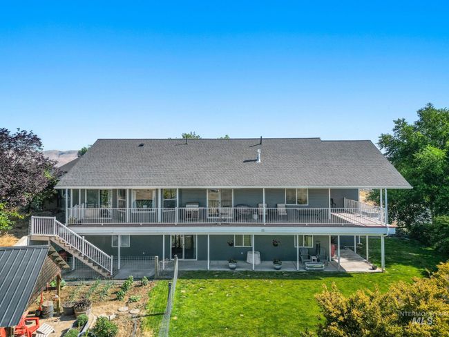 Rear view of property with upper & lower patio/deck areas, a lawn, garden area and a shingled roof | Image 4