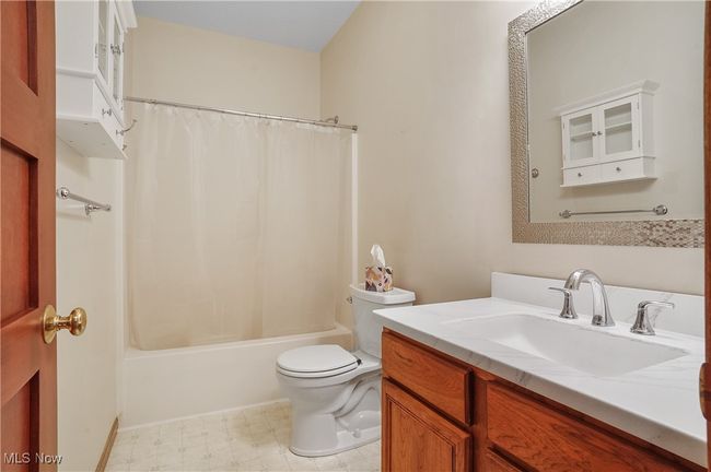 Full bathroom with shower / bath combination with curtain, tile patterned floors, vanity, and toilet | Image 26