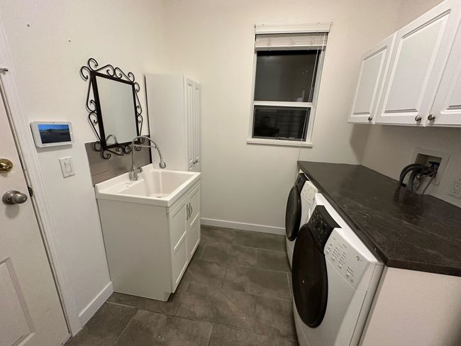 Washroom featuring washer / clothes dryer, baseboards, a sink, and cabinet space | Image 14