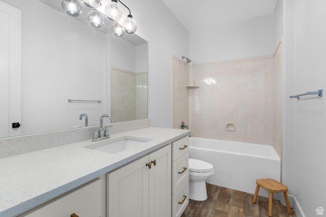 Main floor full bathroom featuring wood finished floors, vanity, and washtub / shower combination | Image 18