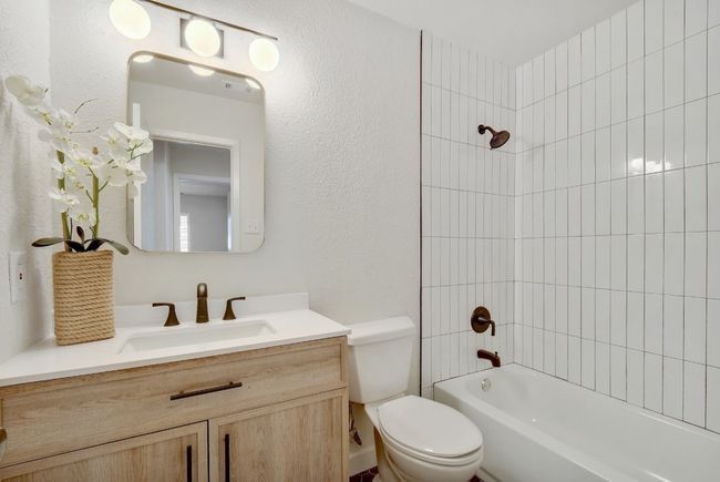 Relax the day away in your new bathtub and enjoy the beautiful updates: linear subway tile, modern matte black hardware and fixtures, hexagonal matte porcelain floor tile, and a natural oak finish vanity. | Image 18