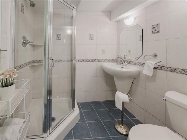 Basement Bathroom with a shower with shower door, tile walls, and toilet | Image 23