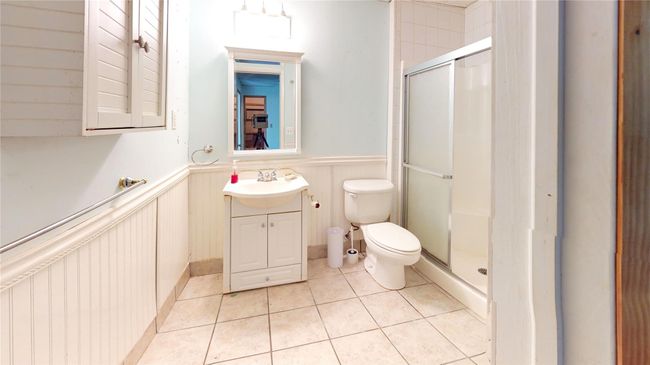 Bathroom featuring tile patterned floors, toilet, a wainscoted wall, and a stall shower | Image 26