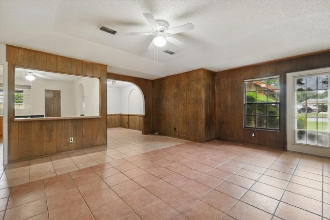 Empty room featuring wooden walls, a ceiling fan, light tile patterned floors, and a textured ceiling | Image 14