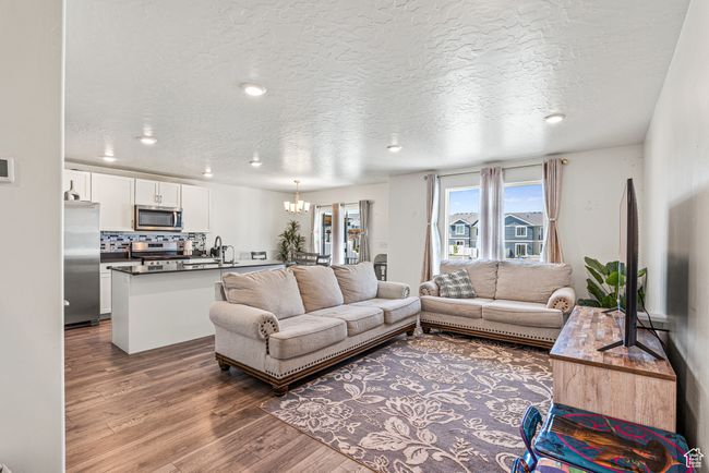 Living room featuring wood finished floors, a chandelier, a textured ceiling, and recessed lighting | Image 9