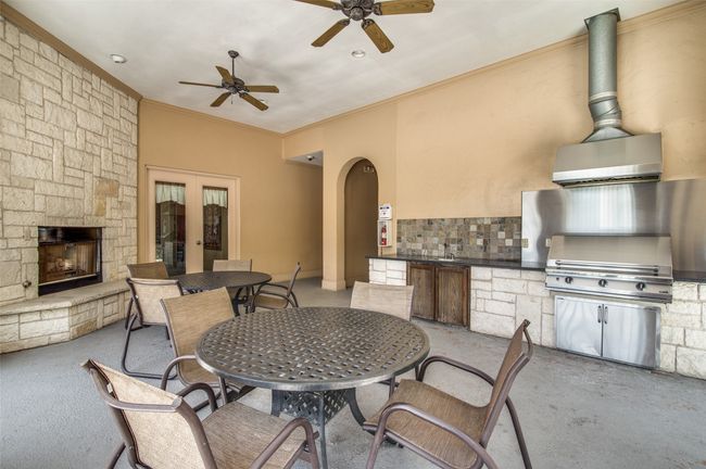 View of patio featuring exterior kitchen, outdoor dining space, a stone fireplace, a ceiling fan, and french doors | Image 29