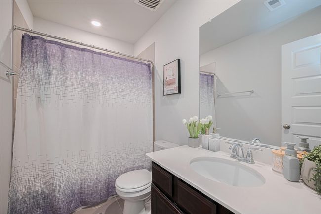 This is upstairs bathroom featuring a modern design with a sleek countertop and sink, a large mirror, and a tub-shower combo with a curtain. | Image 36
