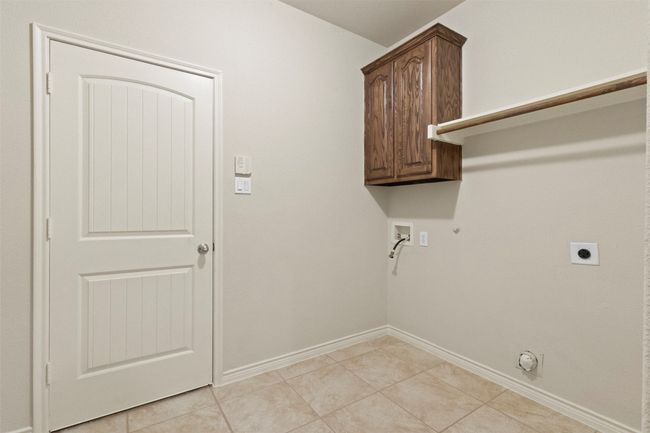 Laundry area featuring hookup for a gas dryer, washer hookup, electric dryer hookup, cabinet space, and light tile patterned floors | Image 20
