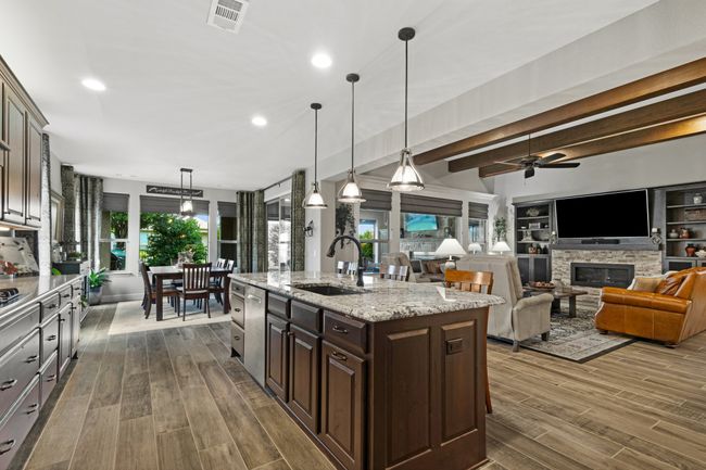 Kitchen featuring a sink, dark wood-style flooring, dark brown cabinets, a fireplace, and beamed ceiling | Image 10