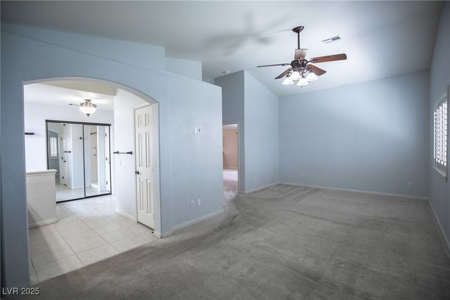 Tiled empty room featuring arched walkways, a ceiling fan, carpet, and baseboards | Image 17