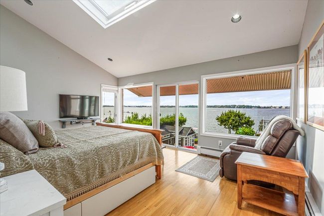 Bedroom with baseboard heating, light wood-style floors, vaulted ceiling, a skylight, and a baseboard heating unit | Image 23