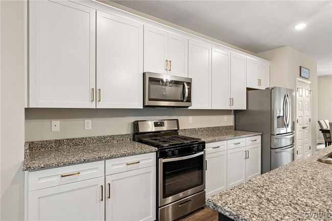 Kitchen featuring light stone countertops, dark wood-type flooring, white cabinets, and stainless steel appliances | Image 18