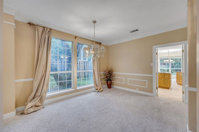 Empty room featuring a chandelier, light carpet, ornamental molding, and healthy amount of natural light | Image 8