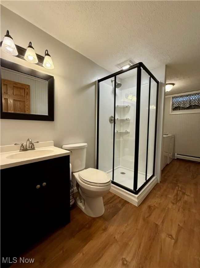 Bathroom with wood finished floors, a shower stall, and a textured ceiling | Image 37