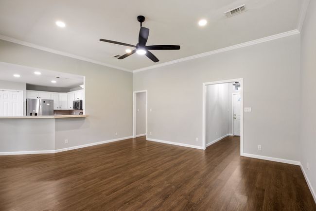 Unfurnished living room with a ceiling fan, ornamental molding, dark wood finished floors, and recessed lighting | Image 27