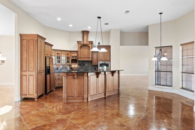 Kitchen with a high ceiling, a chandelier, dark countertops, high end refrigerator, and a kitchen breakfast bar | Image 7