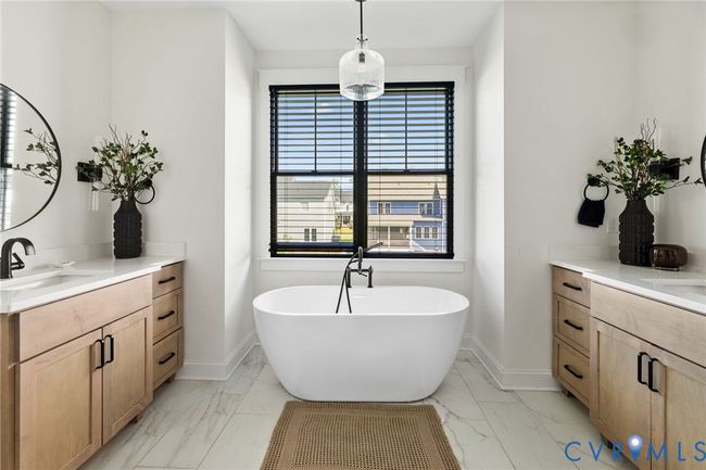 Bathroom with marble look tiles, vanity, and a freestanding tub | Image 36