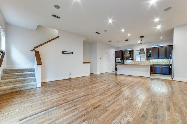 Unfurnished living room featuring visible vents, baseboards, light wood finished floors, and stairs | Image 6