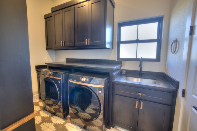 Clothes washing area with cabinet space, washing machine and dryer, baseboards, and a sink | Image 24