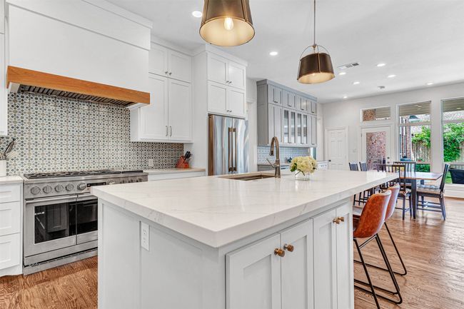 The kitchen island features concealed pull-out trash and recycling bins plus additional seating for quick meals or snacks. | Image 18