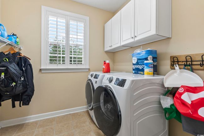 Washroom featuring light tile patterned floors, cabinet space, independent washer and dryer, and baseboards | Image 10