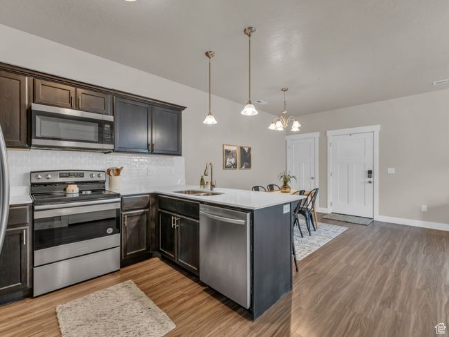 Kitchen with stainless steel appliances, a sink, light wood-type flooring, tasteful backsplash, and a peninsula | Image 5