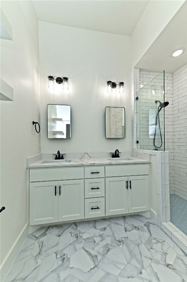 Master bathroom featuring double vanity, walk in shower, and marble finish flooring | Image 25