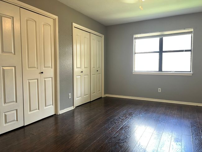 Unfurnished bedroom with multiple closets and dark wood finished floors | Image 12