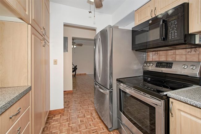 Kitchen with stainless steel electric range, black microwave, a ceiling fan, and light brown cabinetry | Image 18