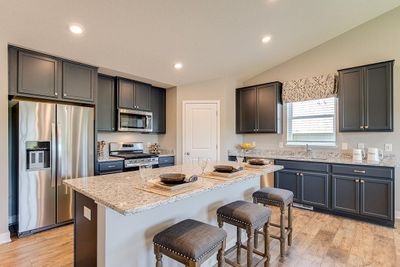 Welcome to the Finnegan! The heartbeat of the kitchen - this Island has loaded of counter space all coated in granite counter-tops with an overhang large enough to fit a handful of bar stools! Photo of model, colors will vary | Image 1