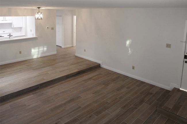 Unfurnished living room featuring dark Luxury Vinyl Plank flooring and a chandelier | Image 12