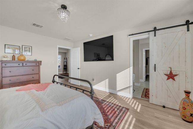 Primary Bedroom with a barn door to the primary bathroom, and light wood finished floors | Image 18