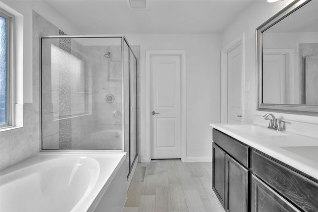 Full bathroom featuring a bath, a stall shower, double vanity, and baseboards | Image 15