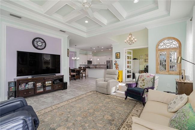 Living room featuring coffered ceiling, ceiling fan with notable chandelier, crown molding, beamed ceiling, and a high ceiling | Image 6