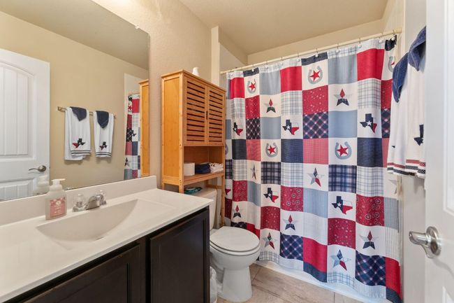 Bathroom with vanity, toilet, a shower with curtain, and tile patterned flooring | Image 12