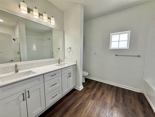 Full bath featuring double vanity, toilet, wood finished floors, and baseboards | Image 15